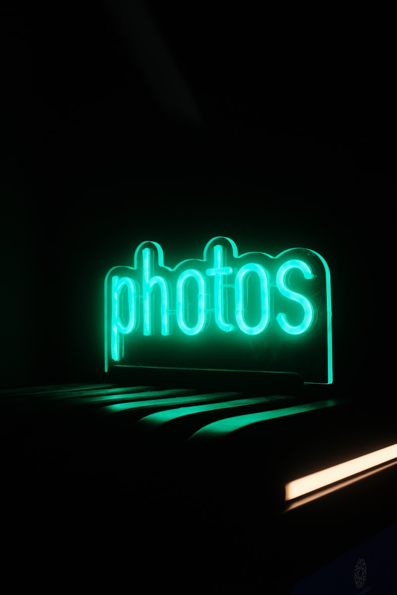 Green neon sign spelling the word photos